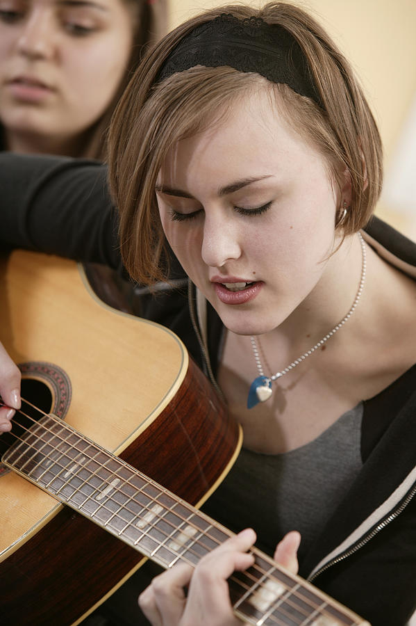 Teenage girl playing guitar Photograph by Comstock Images