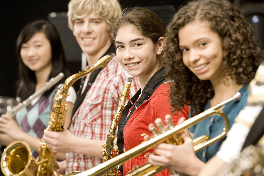 Teenage girl playing saxophone in band Photograph by FangXiaNuo