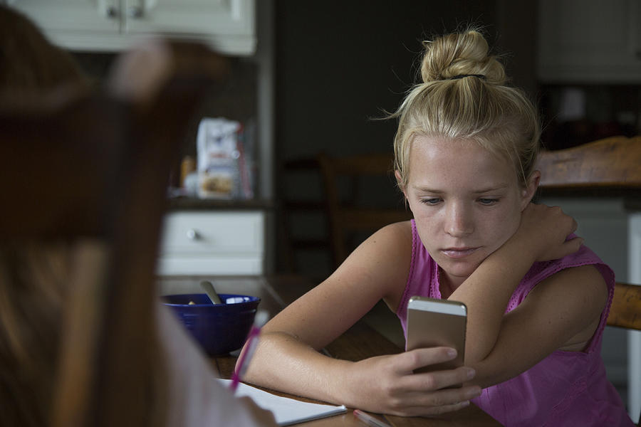 Teenage girl sending text message on smart phone Photograph by The Good Brigade