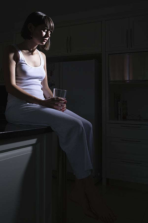 Teenage girl sitting on kitchen counter Photograph by Image Source