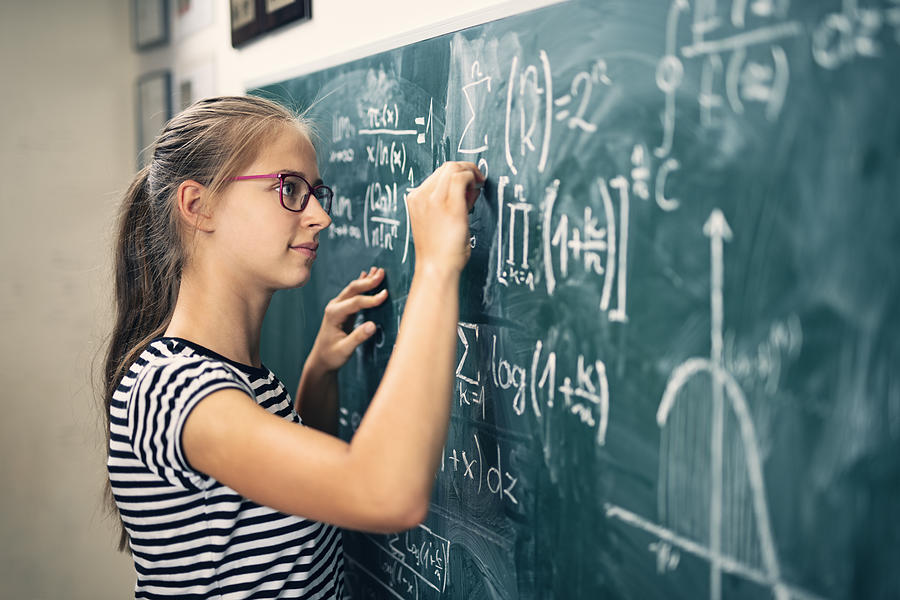 Teenage girl solving advanced mathematical problems Photograph by Imgorthand