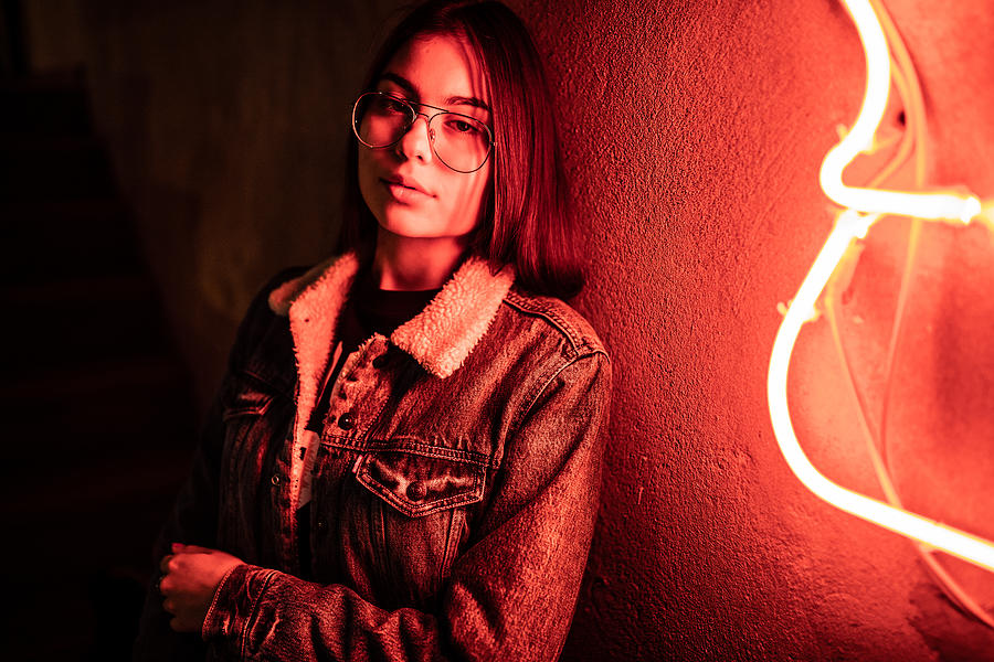 Teenage girl standing next to a neon light Photograph by Domoyega