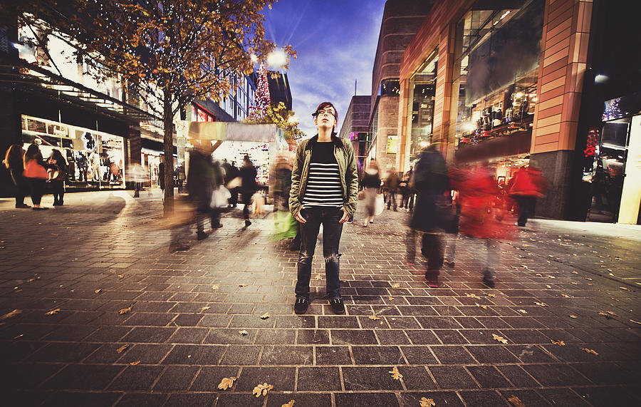 Teenage girl stood still on a busy street Photograph by Sally Anscombe