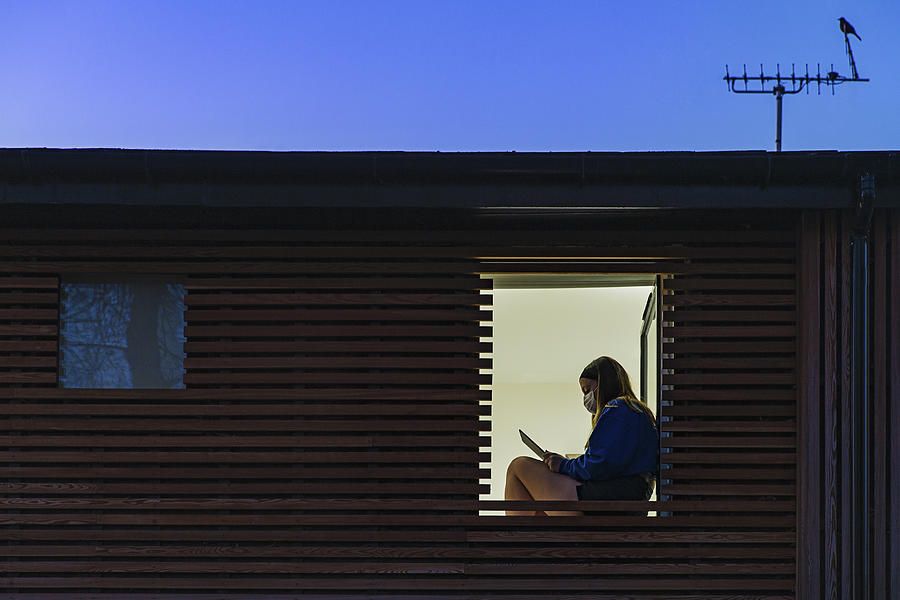 Teenage girl wearing mask sitting in her window Photograph by Justin Paget