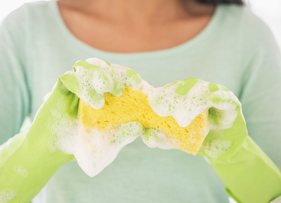 Teenage girl wearing rubber gloves with washing sponge Photograph by Daniel Grill