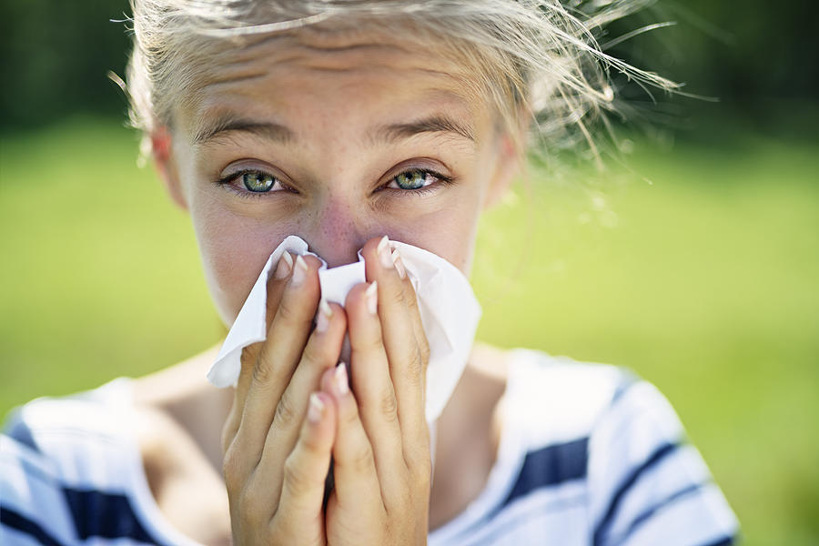 Teenage girl with allergy blowing nose Photograph by Imgorthand