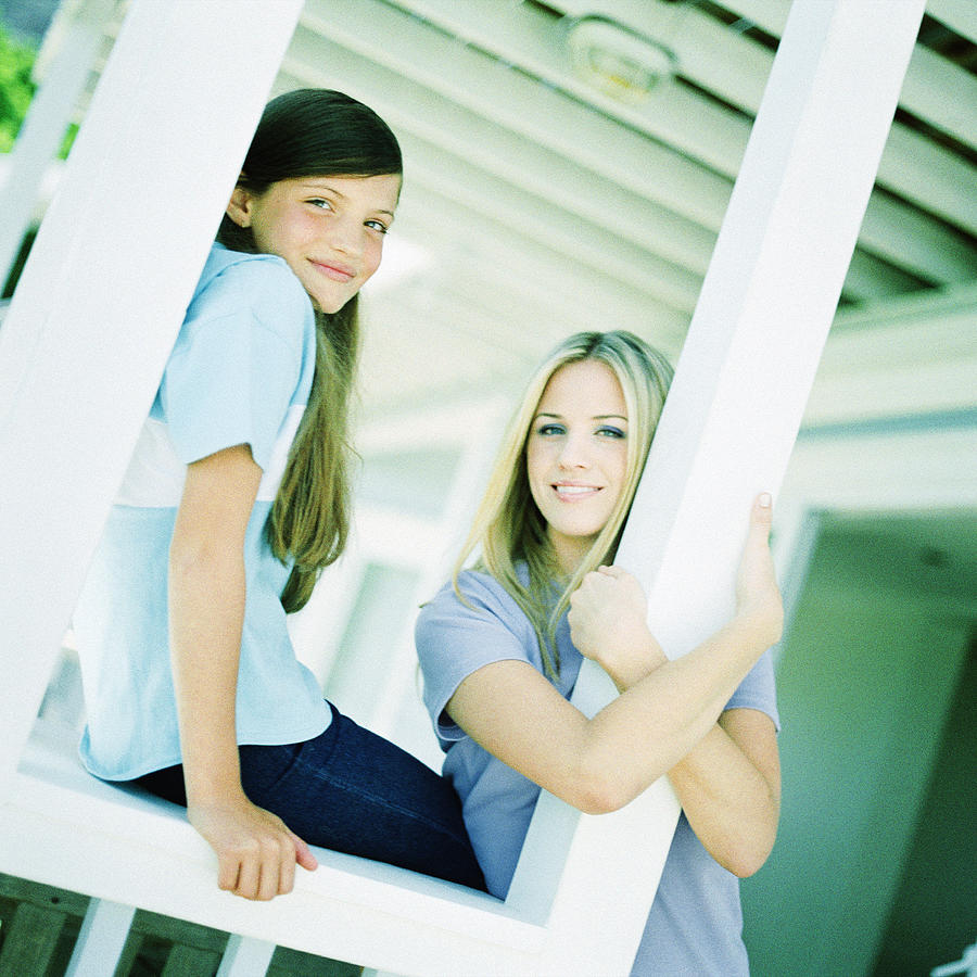 Teenage girls leaning against posts on porch Photograph by Patrick Sheandell OCarroll