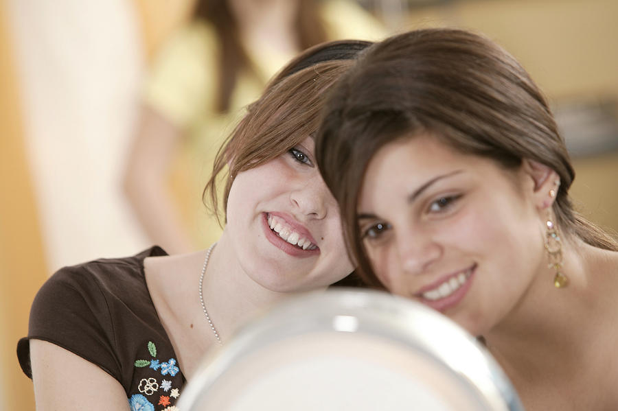 Teenage girls primping themselves with a mirror Photograph by Comstock Images