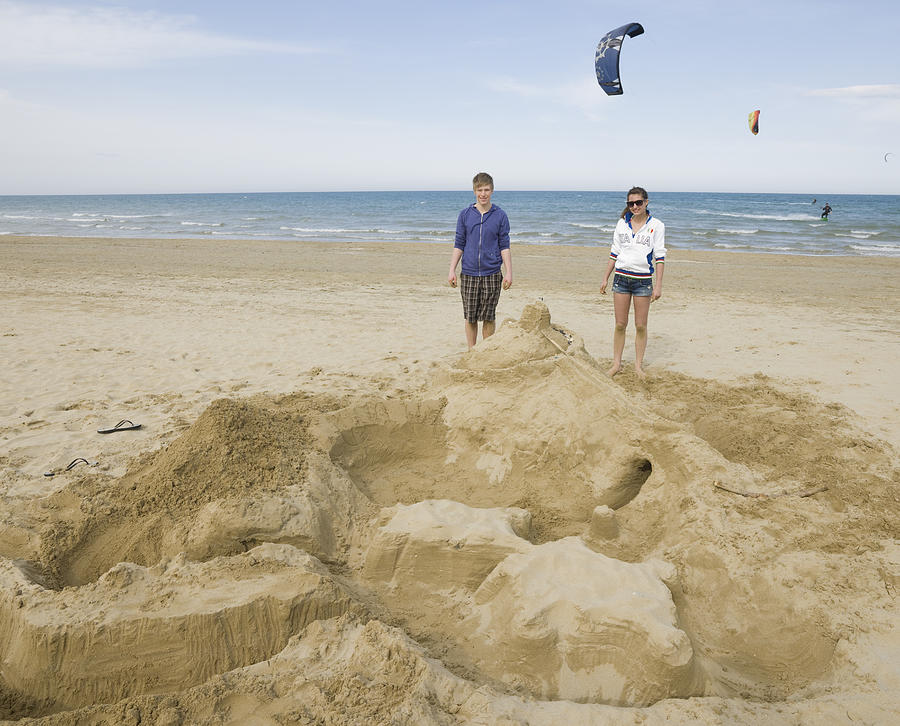Teenage kids beside beach creation, kite surfers Photograph by Ascent/PKS Media Inc.