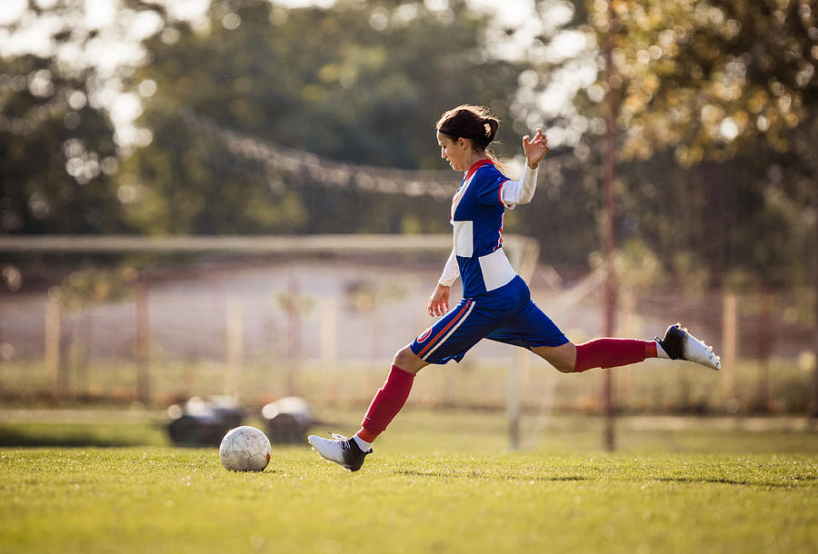 Teenage soccer player about to kick the ball during the match. Photograph by Skynesher