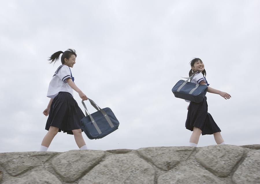 Teenagegirls walking on pier Photograph by Imagenavi