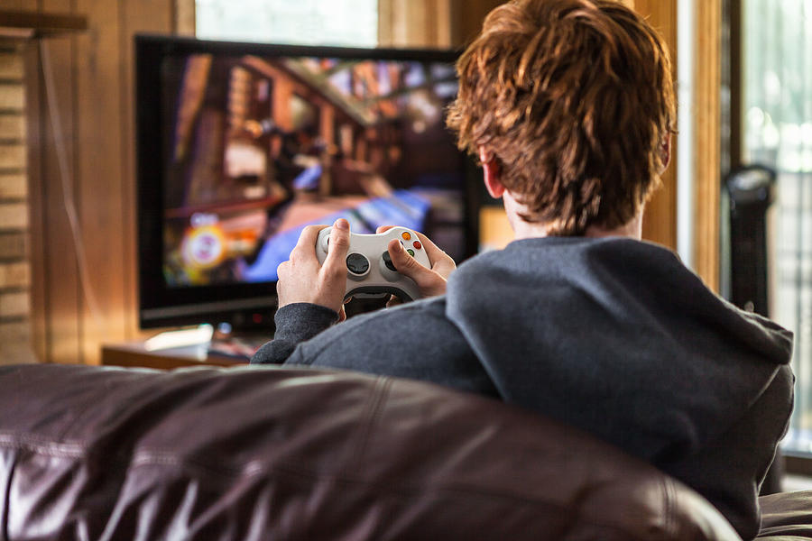 Teenager playing video games at home Photograph by Heshphoto