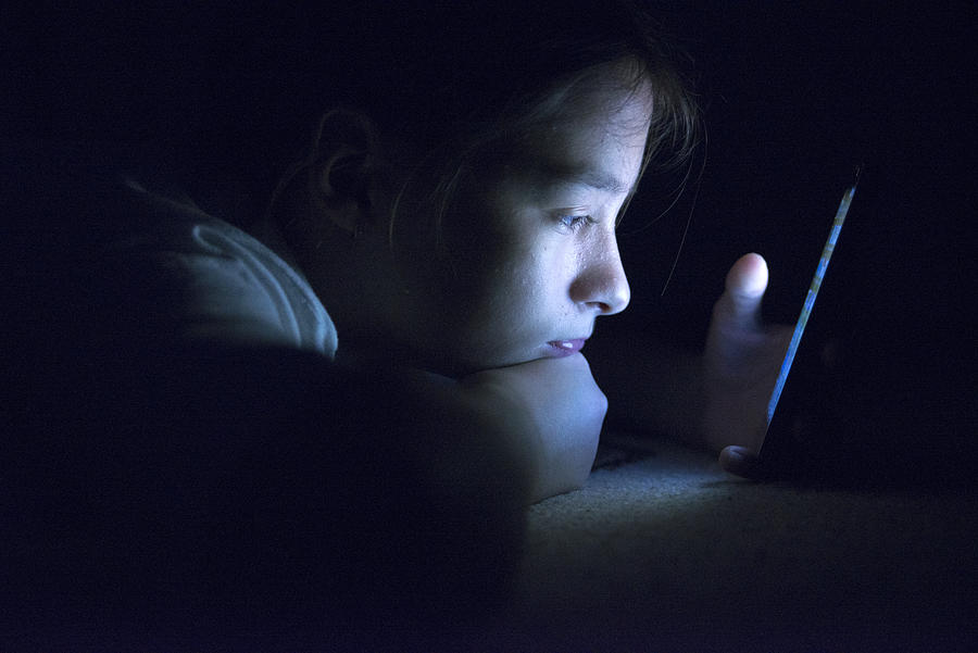 Teenager sending email from smart phone in her bed Photograph by Ljubaphoto