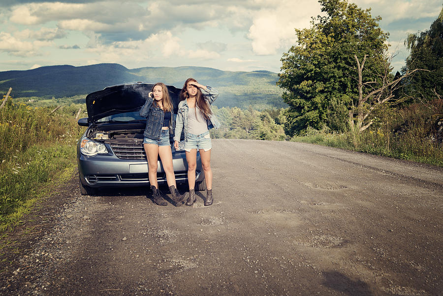 Teenagers in trouble on road with brokedown parents car. Photograph by Martinedoucet