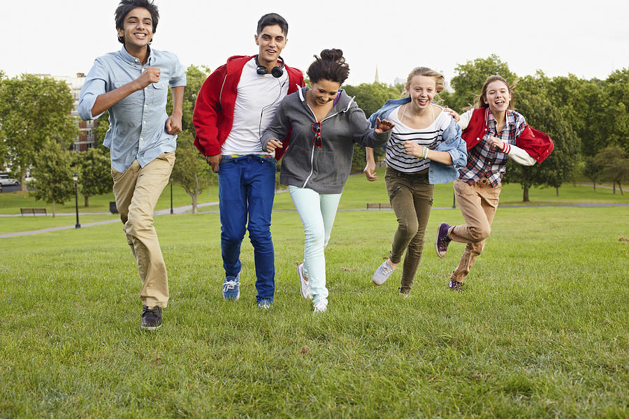 Teenagers running in a park Photograph by Image Source