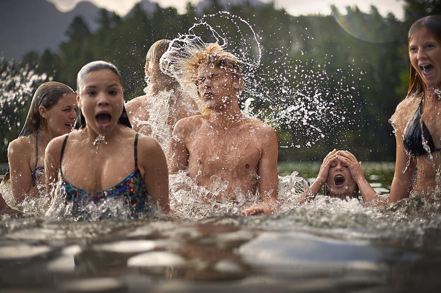 Teenagers splashing in the water Photograph by Tom Wilde