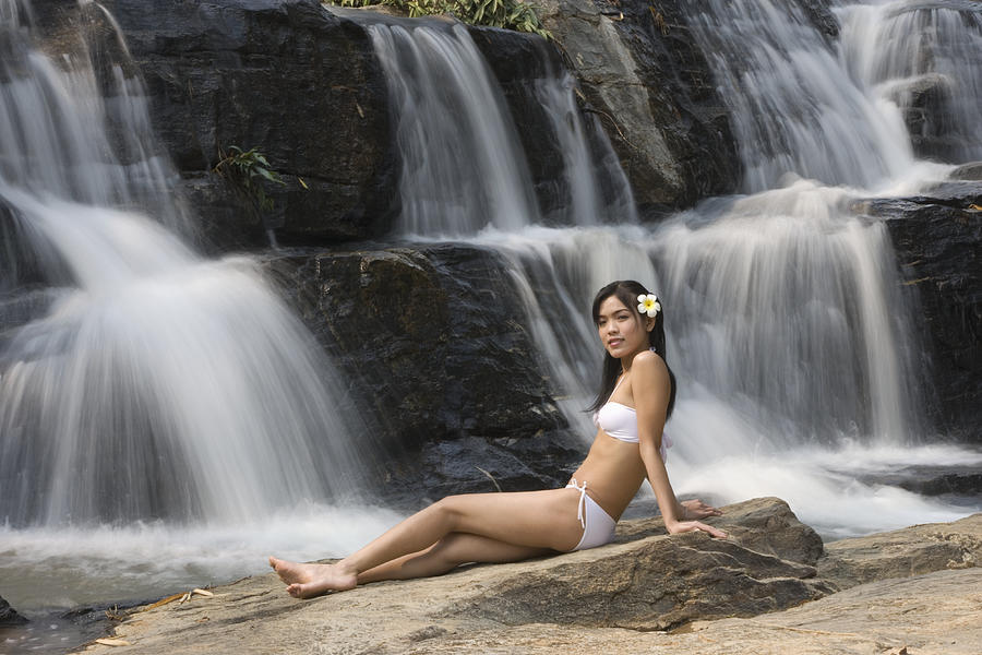 Thailand, Chiang Mai, Sukantara Resort, young woman in bikini reclining by waterfall, side view Photograph by Buena Vista Images