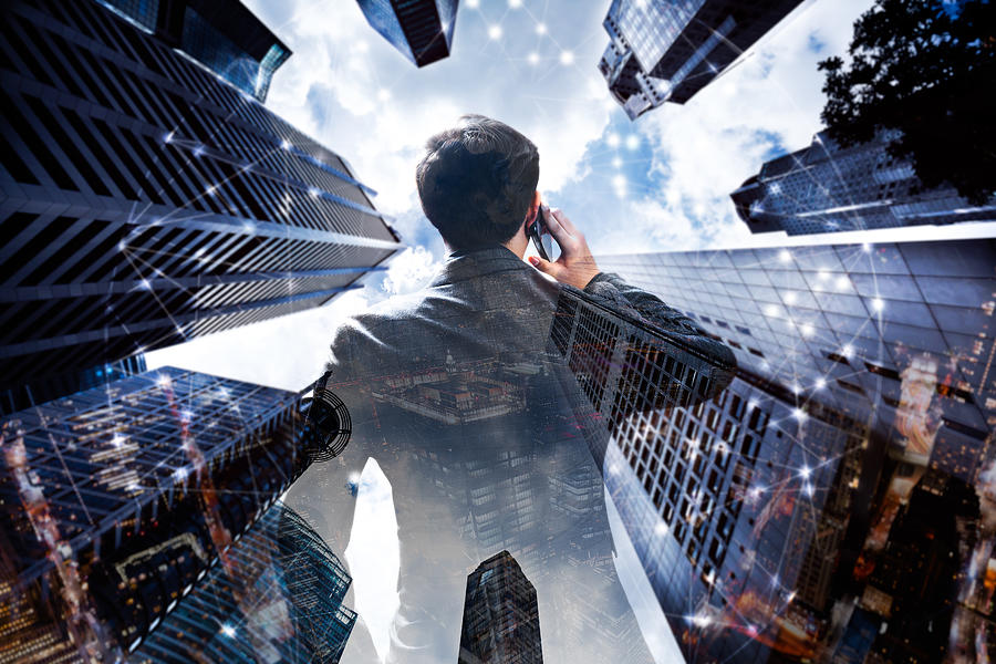 The double exposure image of the businessman with cityscape image and futuristic hologram. The concept, city life and technology future. Photograph by Busakorn Pongparnit