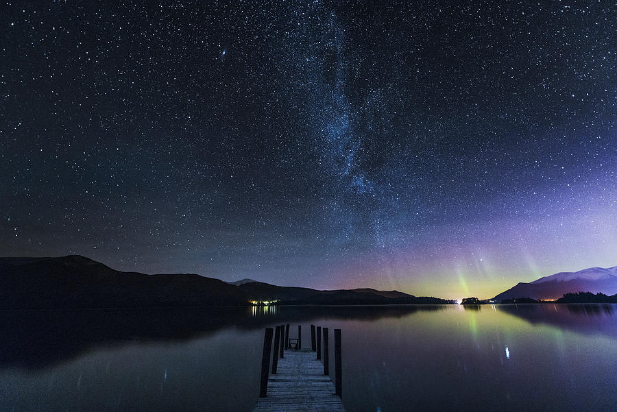 The Milky Way and Aurora Borealis from a jetty over Derwent water. English Lake District. UK Photograph by John Finney Photography