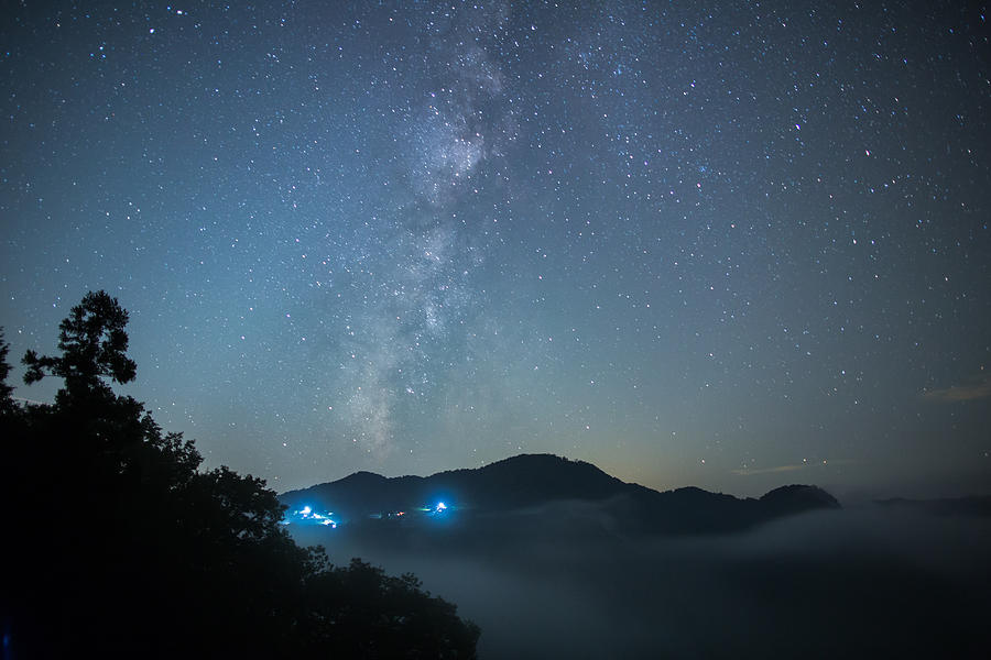 The Milky Way hangs about a valley filled with fog Photograph by Trevor Williams