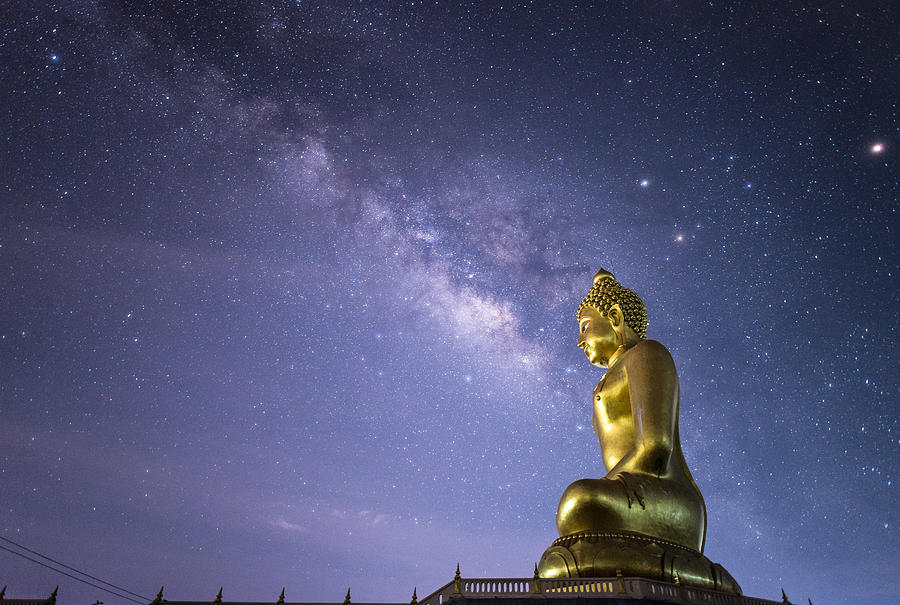 The Milky way over the Big Buddha image in the countryside of Thailand. Photograph by Boy_Anupong