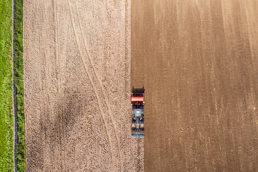 The view from a drone looking directly down on a tractor being used to pull a seed drill on a Scottish farm on a late summer day Photograph by JohnFScott