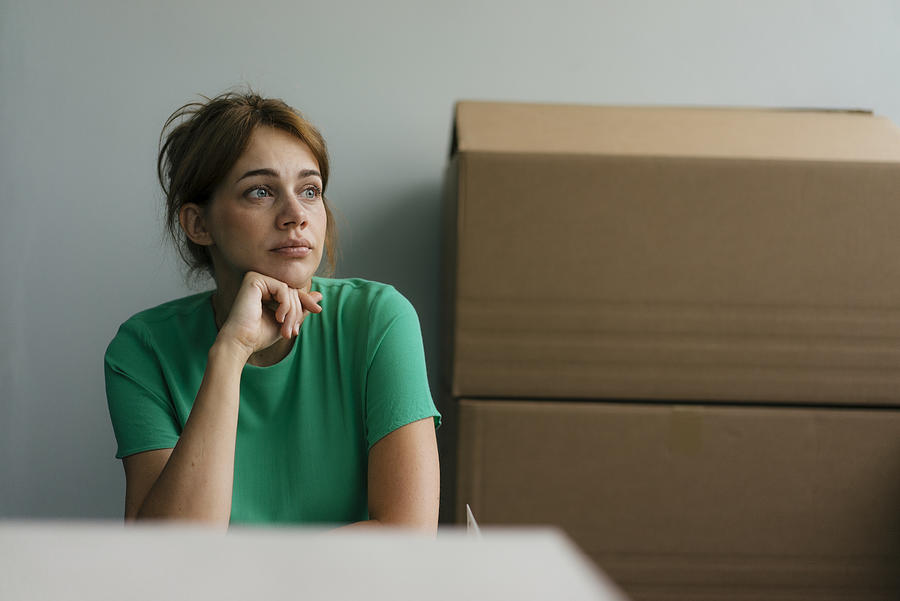 Thoughtful woman next to cardboard boxes in office Photograph by Westend61
