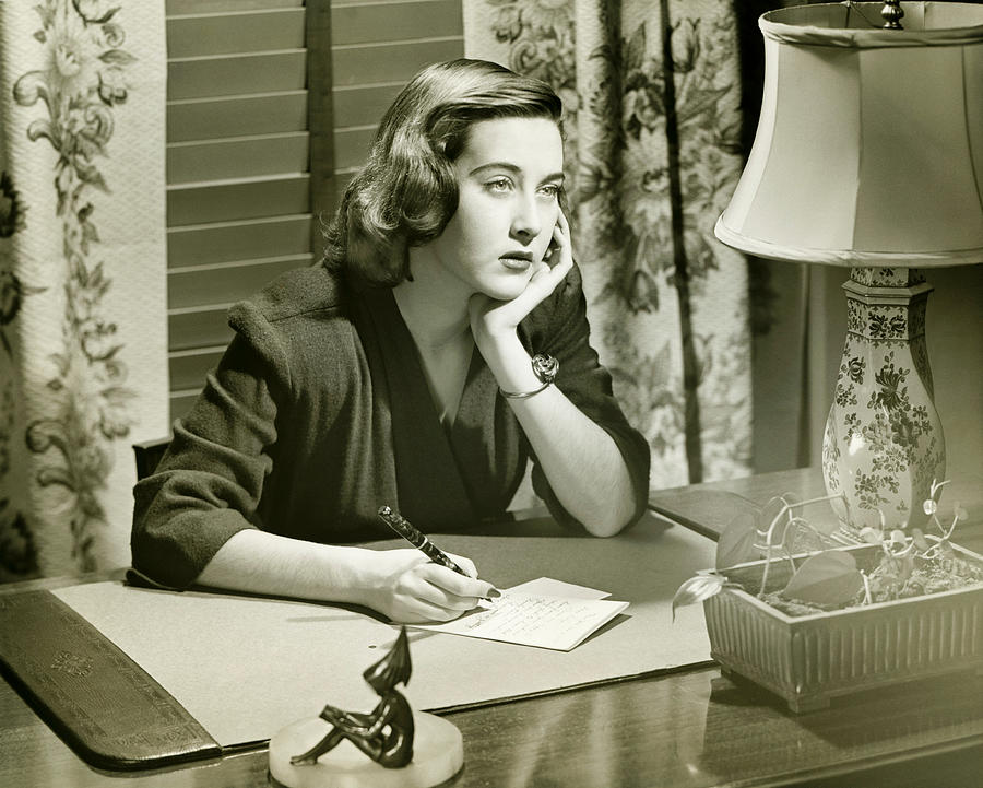 Thoughtful woman writing letter at desk, (B&W) Photograph by George Marks