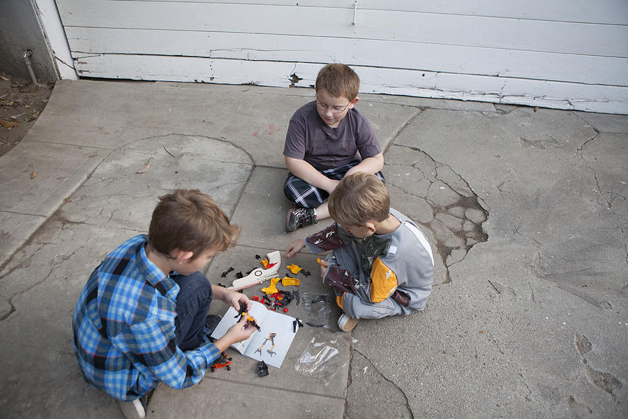 Three boys putting together a toy Photograph by Catherine Ledner