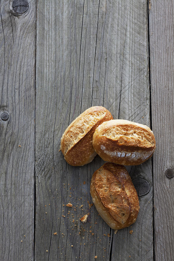 Three bread rolls on grey wood Photograph by Westend61