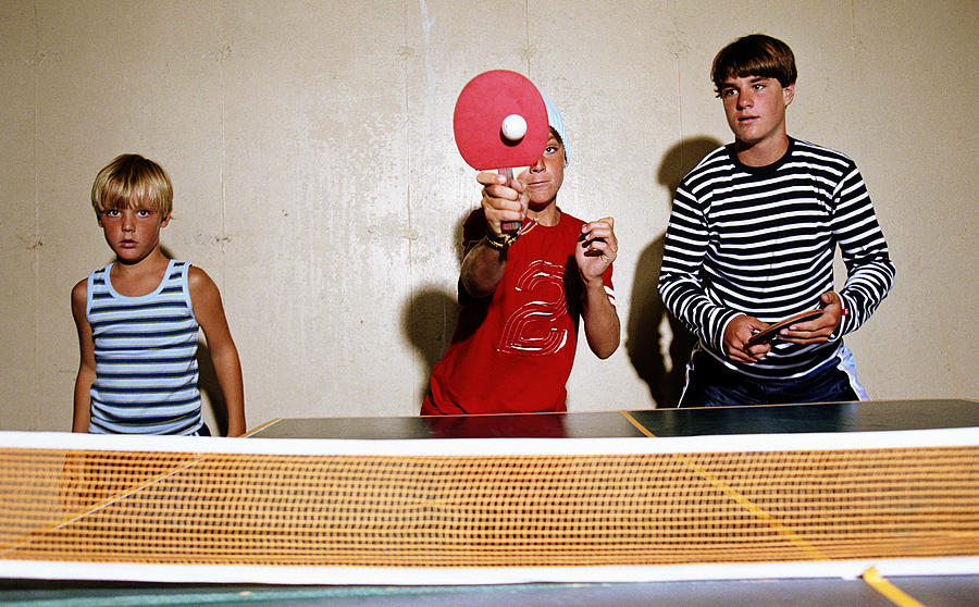 Three brothers (8-15) playing table tennis Photograph by Sean De Burca