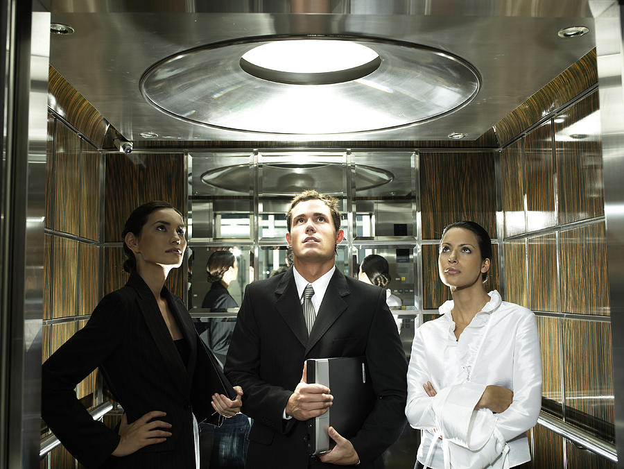 Three business colleagues standing in elevator Photograph by Hans Neleman