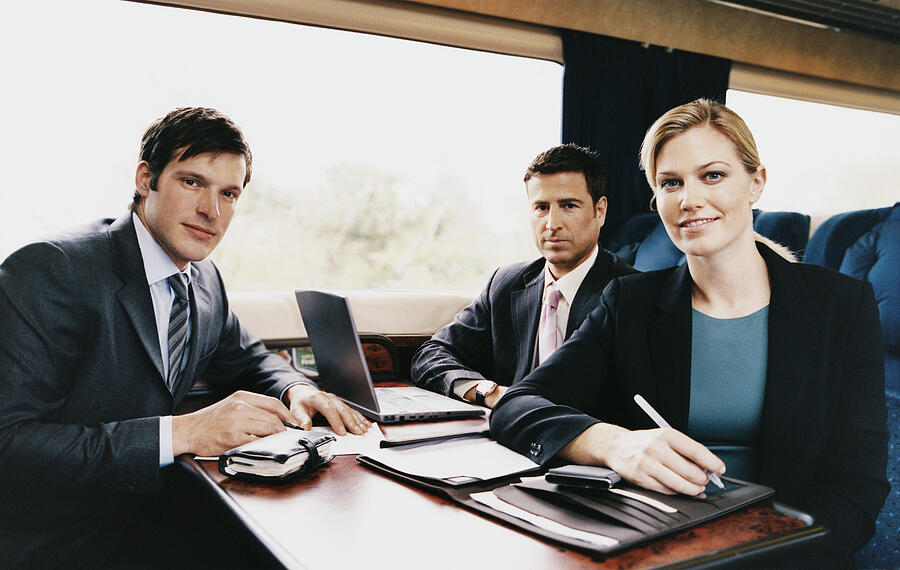 Three Business Executives Sitting at a Table on a Passenger Train Photograph by Digital Vision.