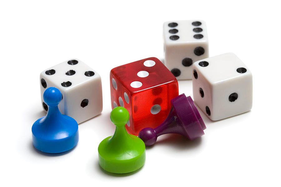 Three colored game pieces and four dice on white background Photograph by Jsolie