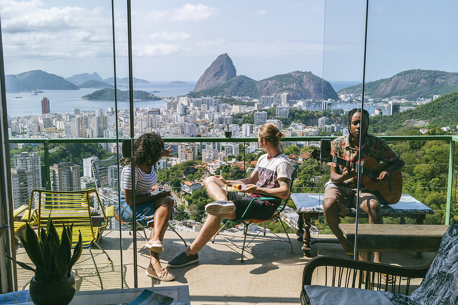 Three friends on balcony with views of Sugarloaf Mountain Photograph by JohnnyGreig