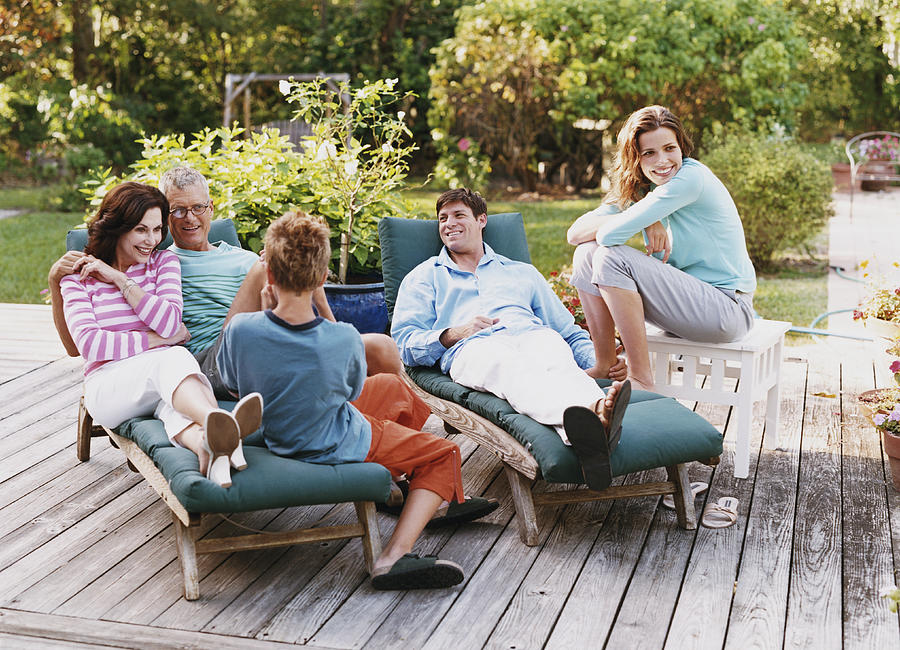 Three Generational Family Sit on Decking in Their Garden Photograph by Digital Vision.
