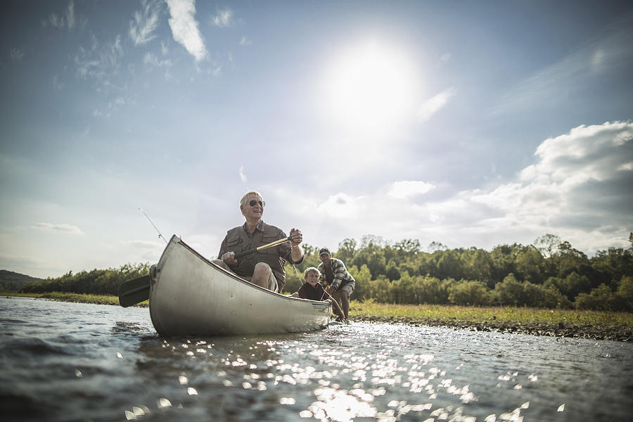 Three generations of Caucasian men paddling canoe in river Photograph by John Fedele