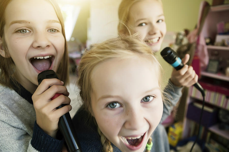 Three girls singing with microphone Photograph by Westend61
