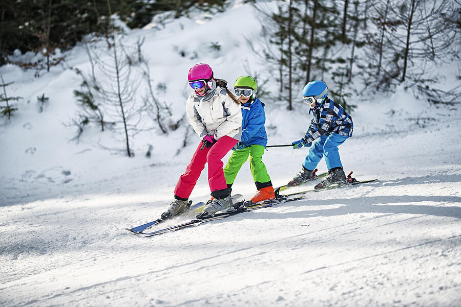 Three kids having fun skiing together on sunny winter day Photograph by Imgorthand