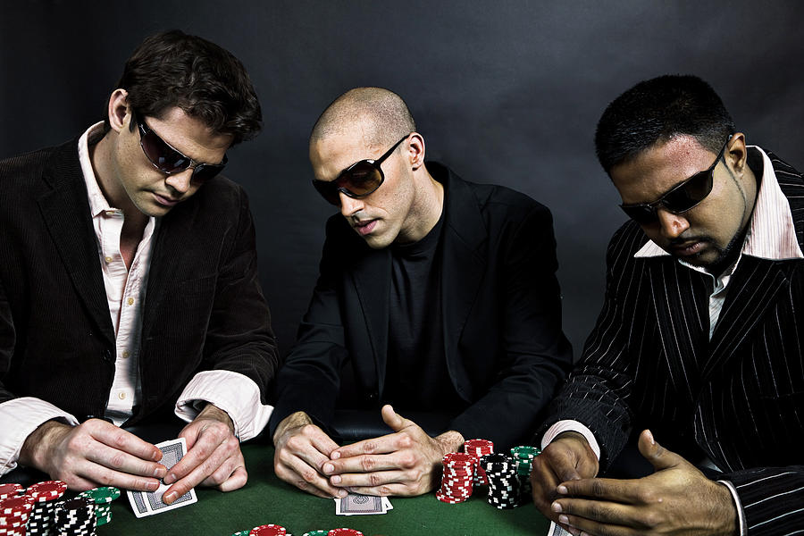 Three Men Sitting at Table Playing Poker and Checking Cards Photograph by Arsenik