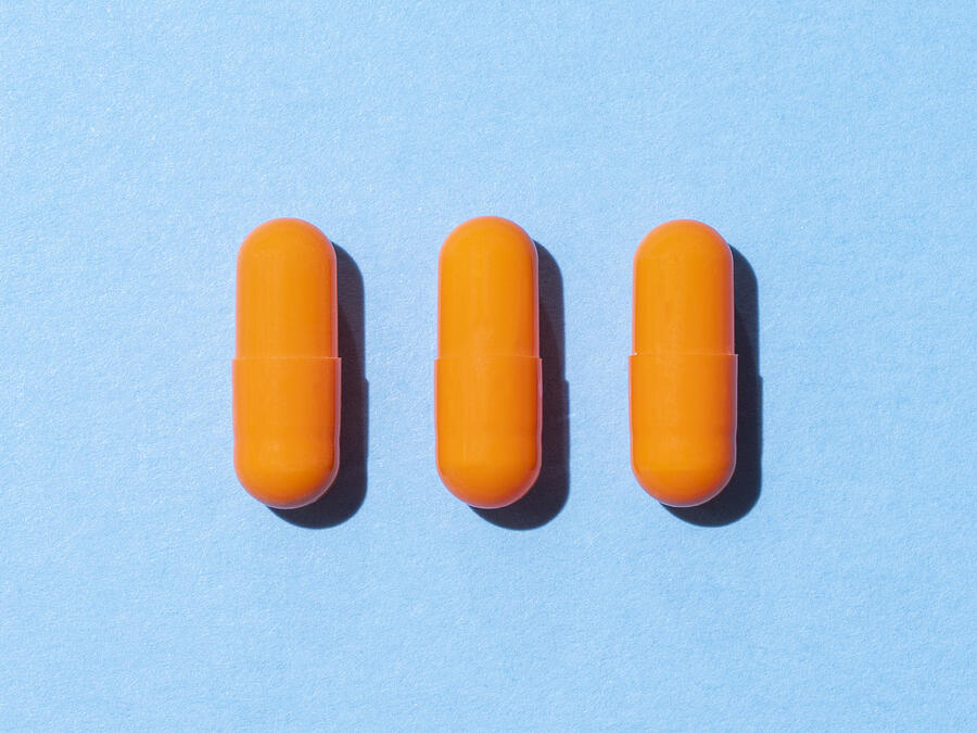 Three Orange Pills On A Blue Colored Background Photograph by Javier Zayas Photography