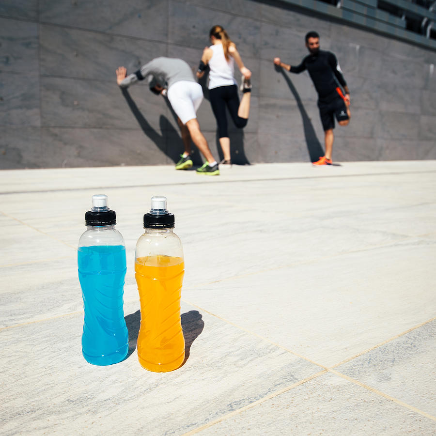 Three people stretching with blue and orange drinks Photograph by FilippoBacci