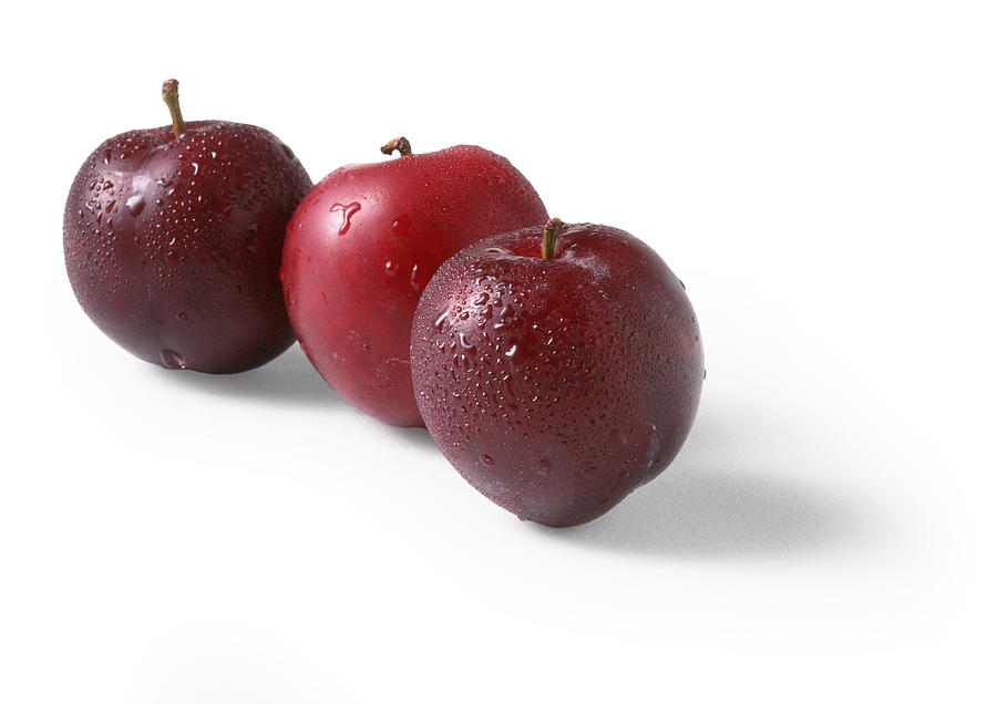 Three red plums, white background Photograph by Isabelle Rozenbaum