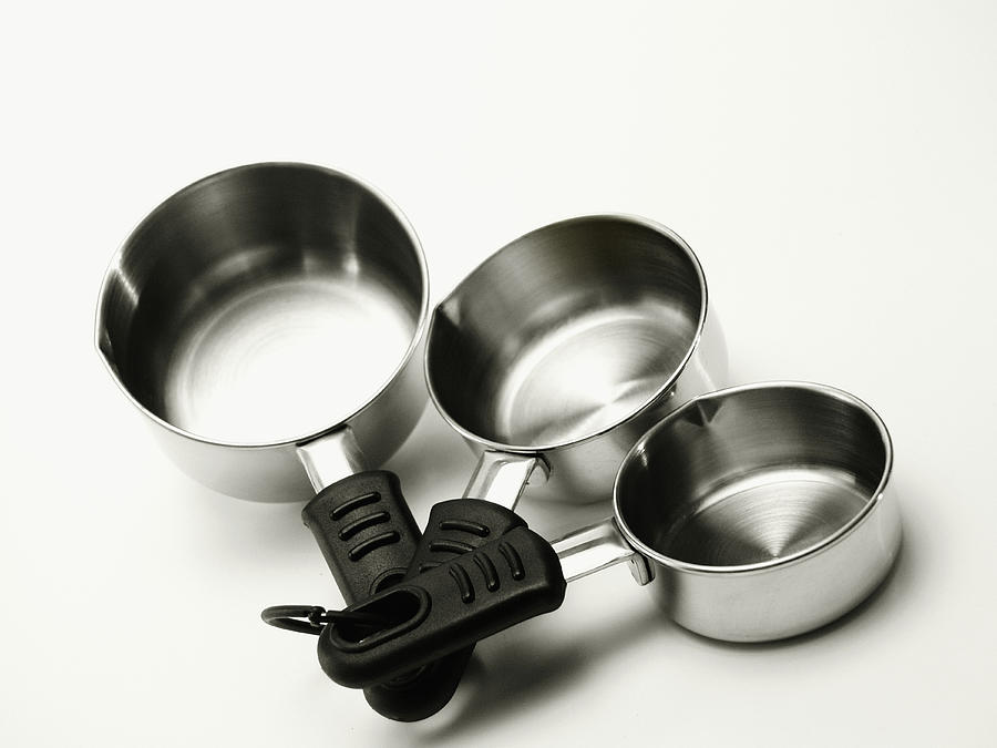 Three stainless steel measuring cups with rubber handles Photograph by Medioimages/Photodisc