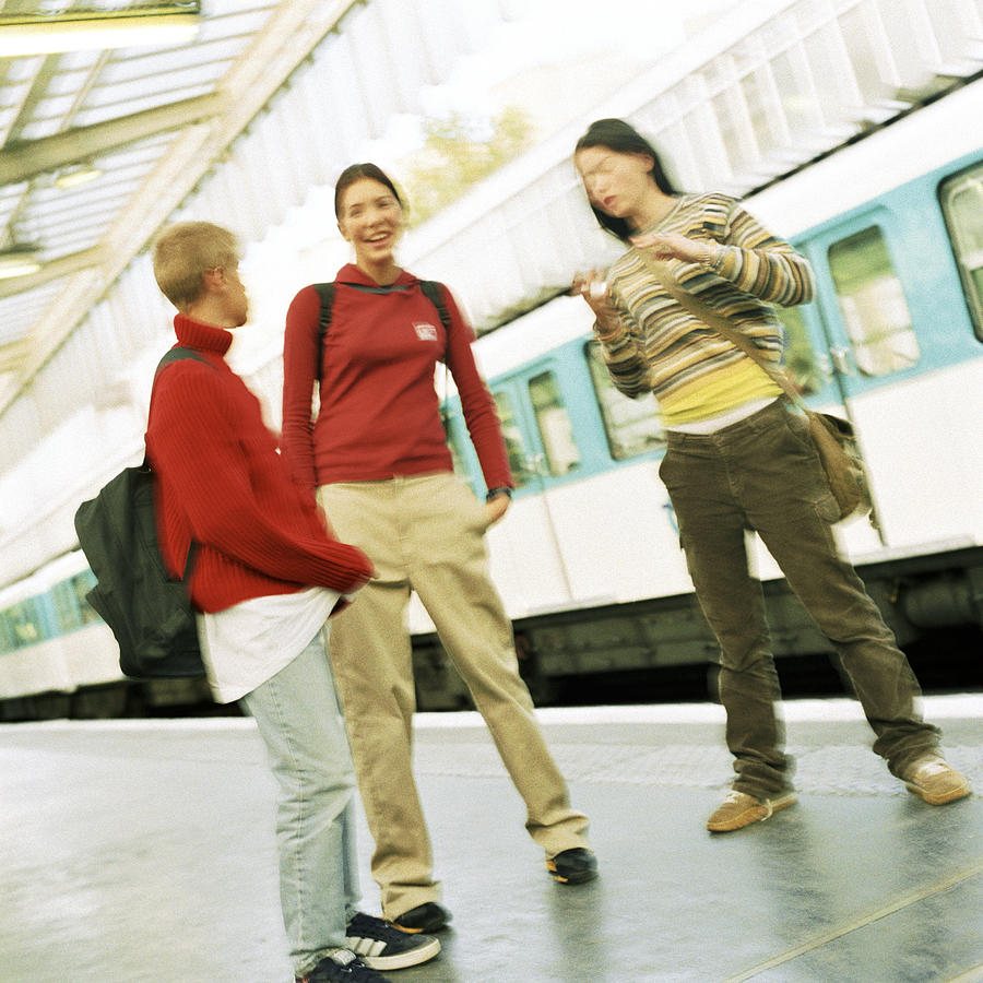 Three teenagers standing on subway platform, blurred Photograph by Patrick Sheandell OCarroll