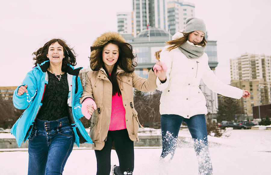 Three young women running in snow holding hands Photograph by Aleksander Rubtsov