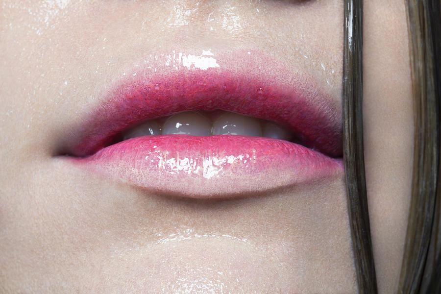 Tight crop of young womans juicy red lips. Photograph by Andreas Kuehn