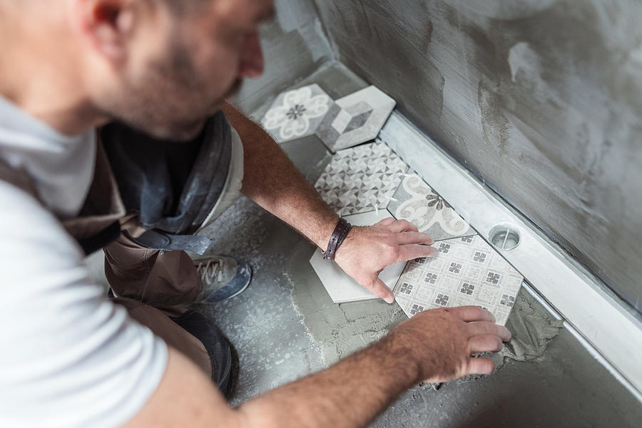 Tiler installing tiles on the bathroom floor Photograph by Mixmike