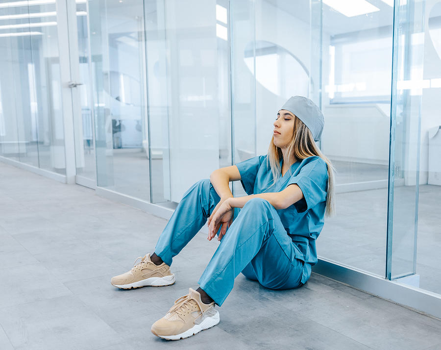 Tired Female Medical Professional Taking Break in Hospital Corridor Photograph by Serts