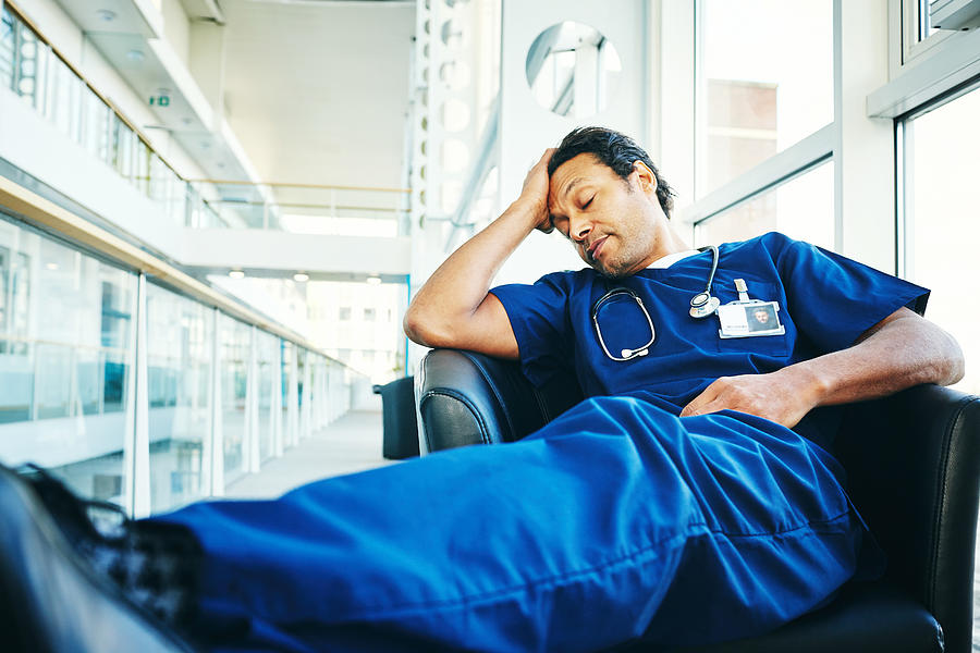 Tired medical professional sleeping in hospital lounge Photograph by Dean Mitchell